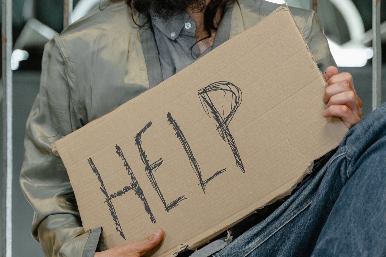 Mastering the First Impression: Your intriguing post title goes here Close-up shot of a person holding a cardboard help sign, highlighting urban poverty.