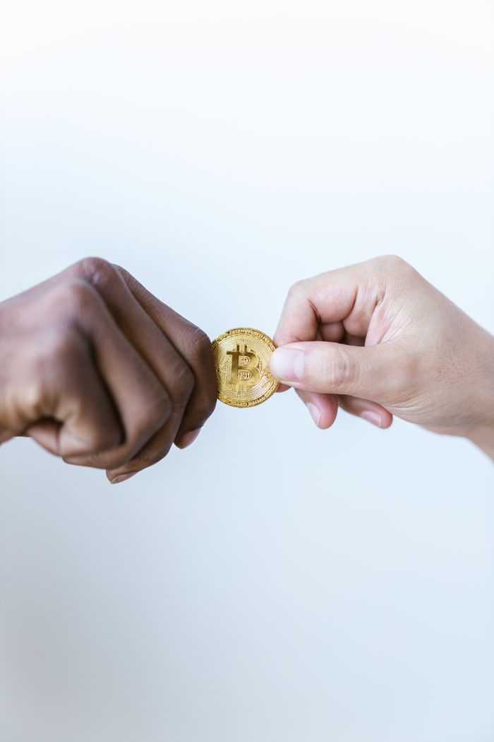 Crafting Captivating Headlines: Your awesome post title goes here Close-up of two diverse hands exchanging a gold bitcoin coin, symbolizing cryptocurrency trade.